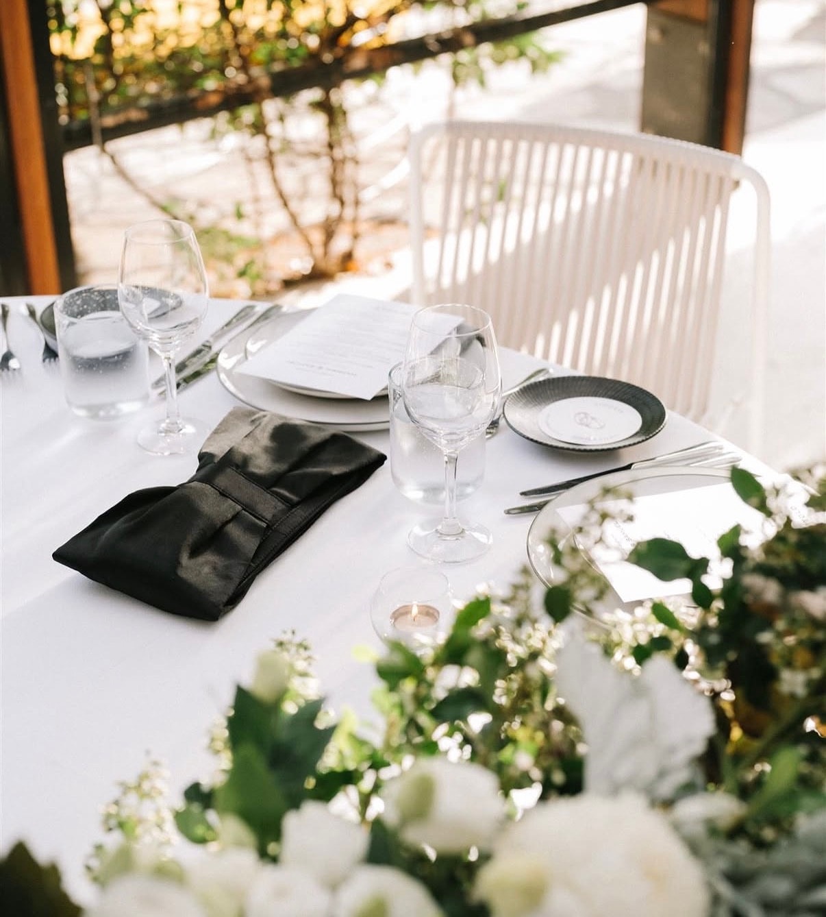 Wine and champagne glasses beside protea flowers on a sunlit table
